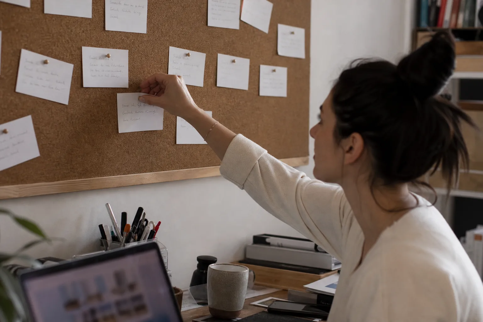 Index cards with handwritten strategy rules pinned to a cork board above a desk