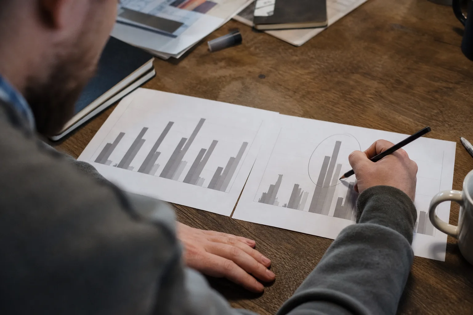 Two printed volume bar charts side by side on a desk with a pencil circling the taller bars